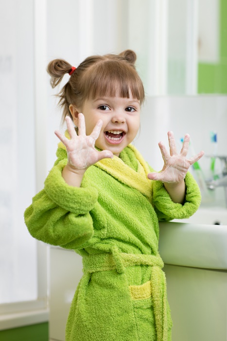 child washing hands and showing soapy palms