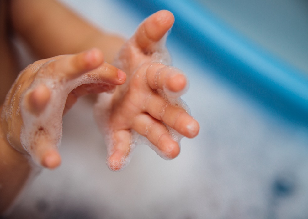 Baby pens in a blue bubble bath. Baby detergent, hygiene. Baby skin care. Background, texture of soap bubbles.