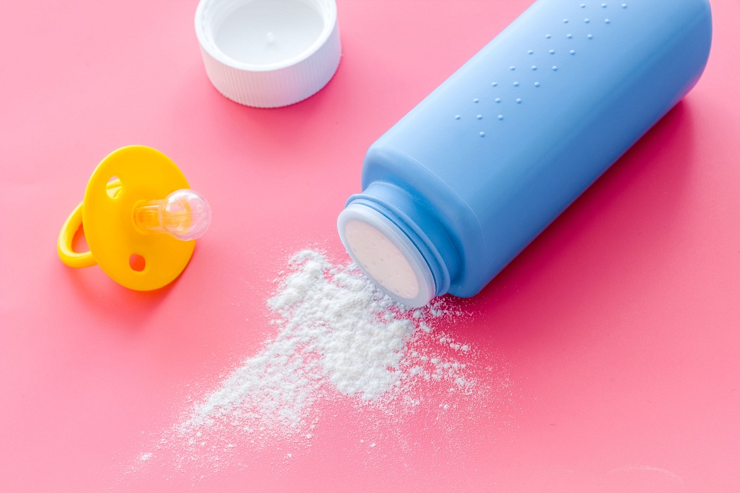 Baby talcum powder for delicate skin care near pacifier on pink background.