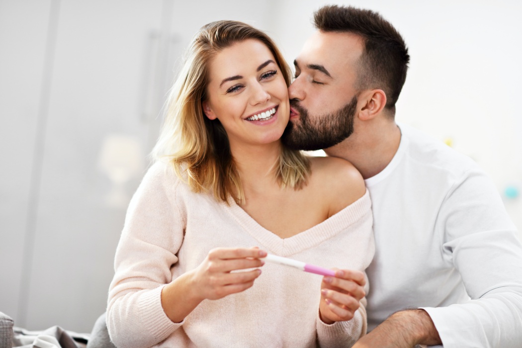 Picture showing happy couple with pregnancy test in bedroom