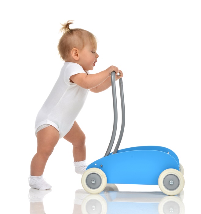 Cute smiling baby girl toddler with toy walker make first steps