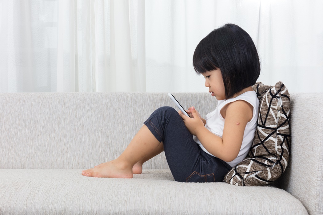 Asian Chinese little girl lying on the sofa with phone