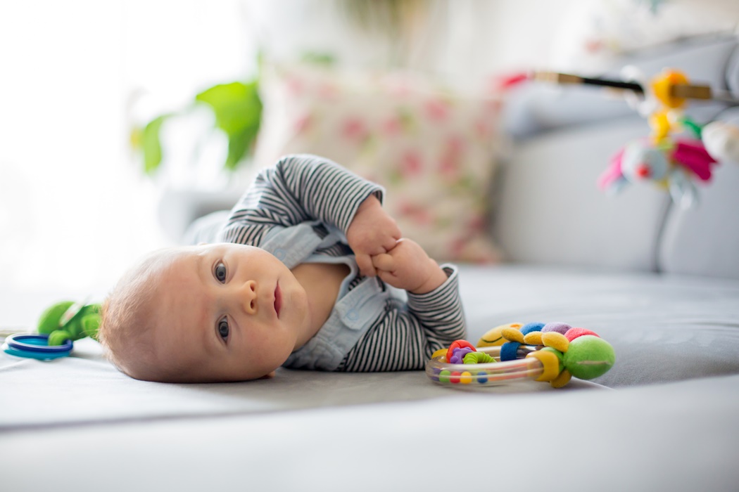 Cute baby boy, playing with toys in a sunny living room