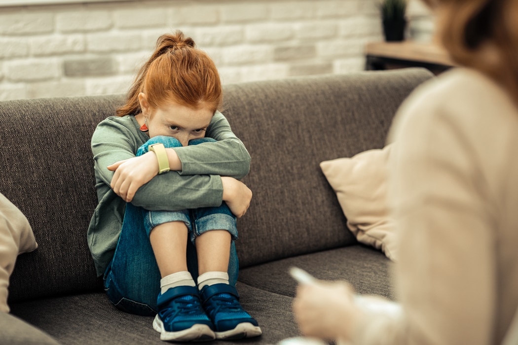 Depressed cute cheerless girl hugging her legs