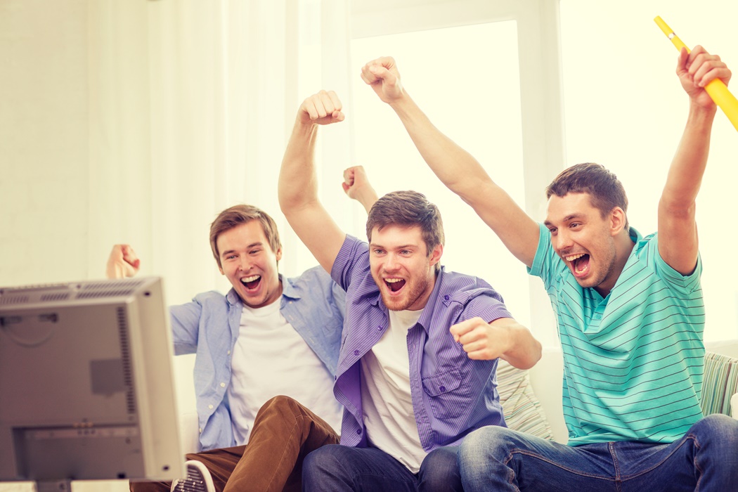 happy male friends with vuvuzela watching sports