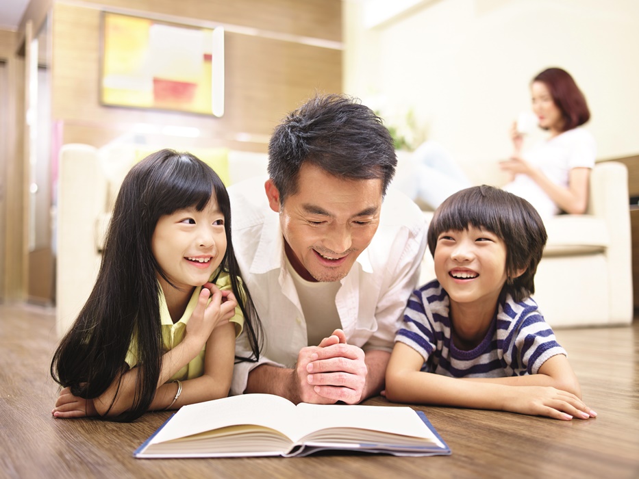 asian father and children reading book together
