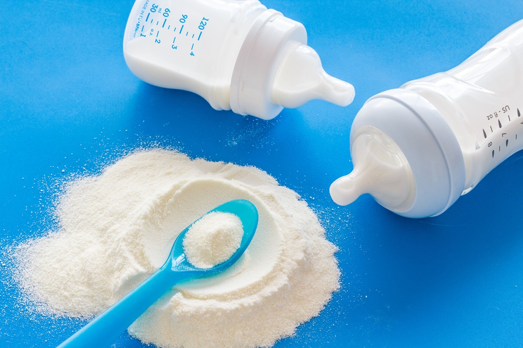 Powdered food for newborn baby near baby bottle on blue background