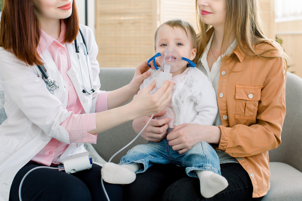 woman doctor hold a mask vapor inhaler for little baby girl . infant baby receives a nebulizer treatment through the facial mask.