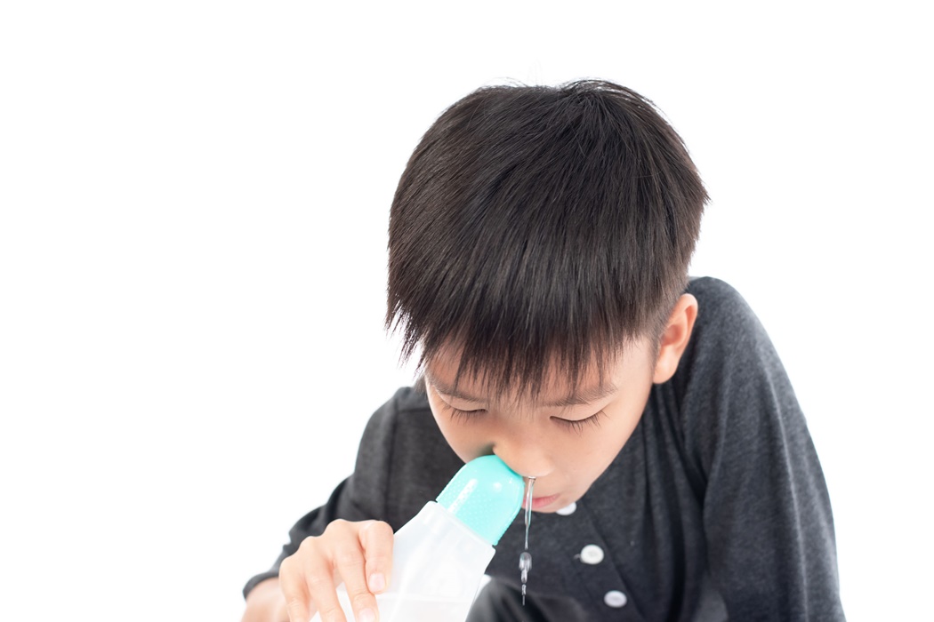 Young boy use saline water to clean his nasal.