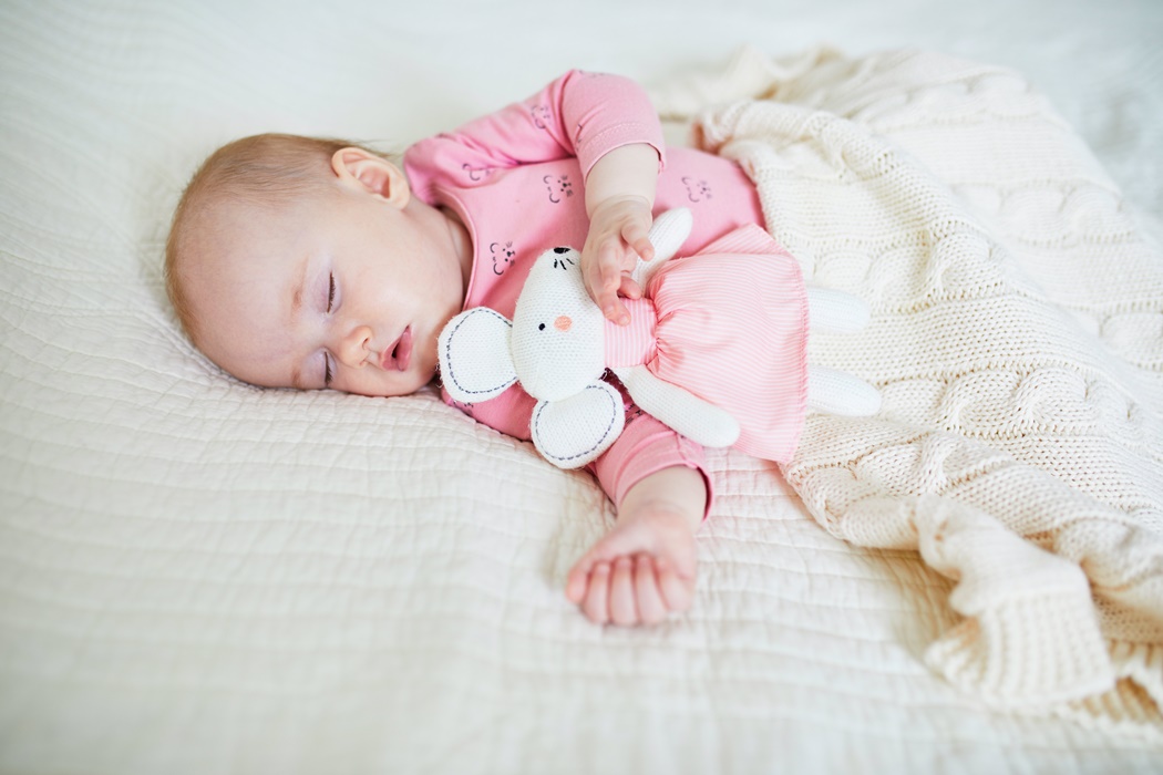 Baby having a nap with her favorite mouse toy