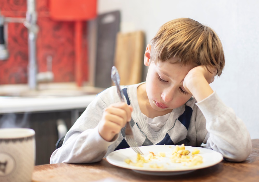 The child does not want to eat. Poor appetite. A boy sits over a plate with tears