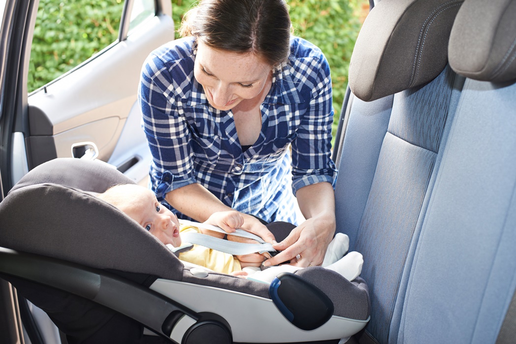 Mother Putting Baby Into Car Seat For Journey