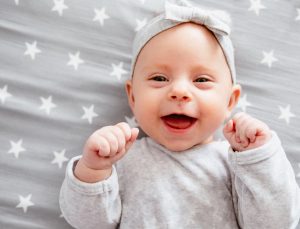 Happy laughing baby girl on her bed.