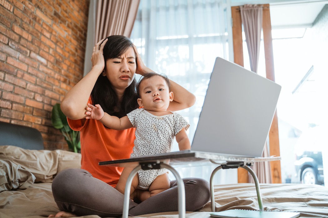 asian young woman working while taking care of her children at home