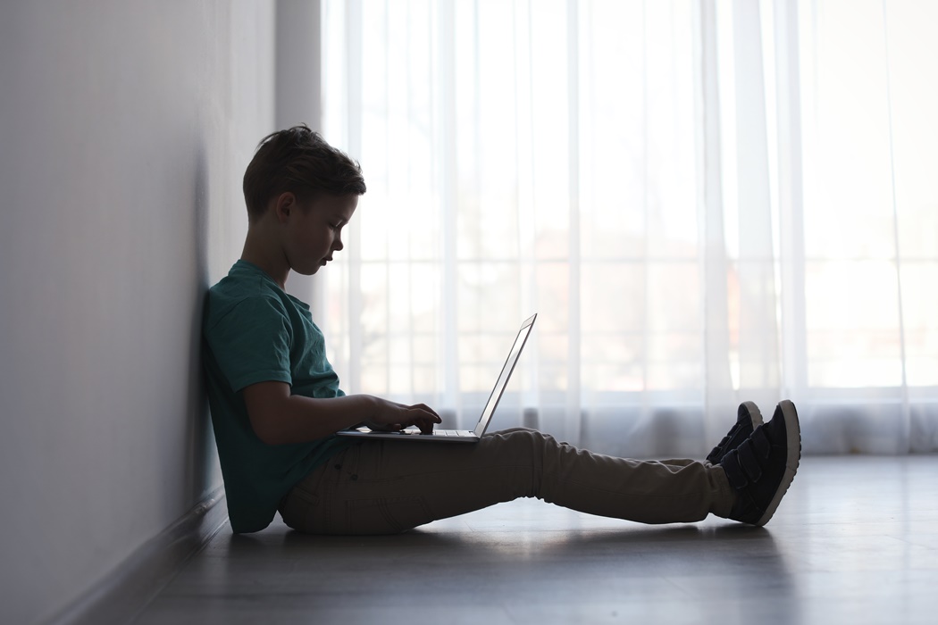 Little child with laptop on floor indoors, space for text. Danger of internet