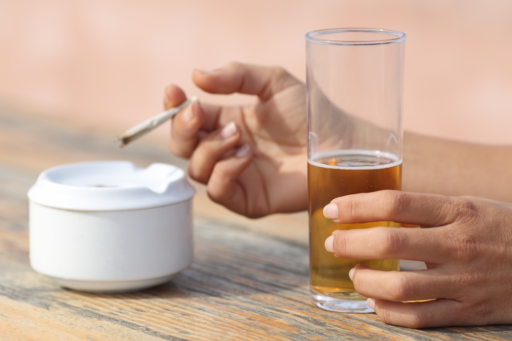 Hands holding a cigarette smoking and drinking alcohol