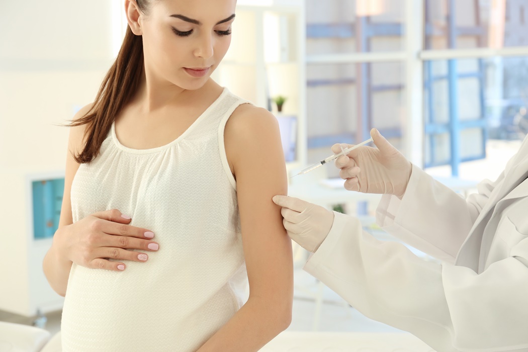 Young pregnant woman receiving vaccination in clinic