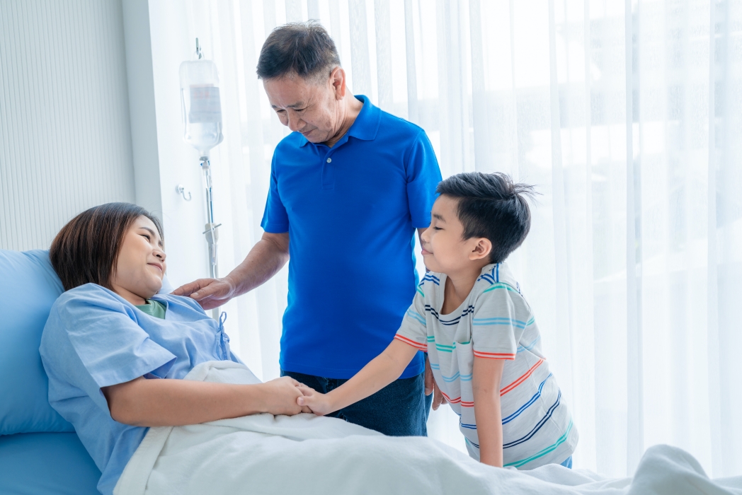 Asian woman, sick, stay in hospital. lying on the patient's bed beside the window A son and family came to visit and encourage