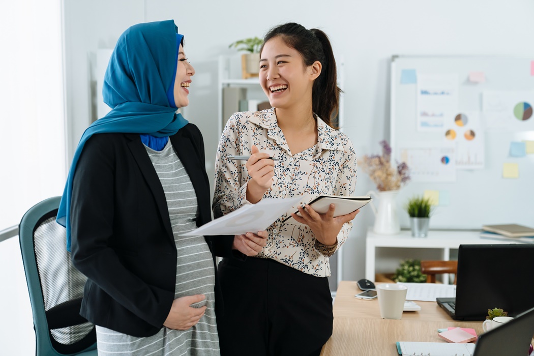 pregnant muslim woman with colleague having fun