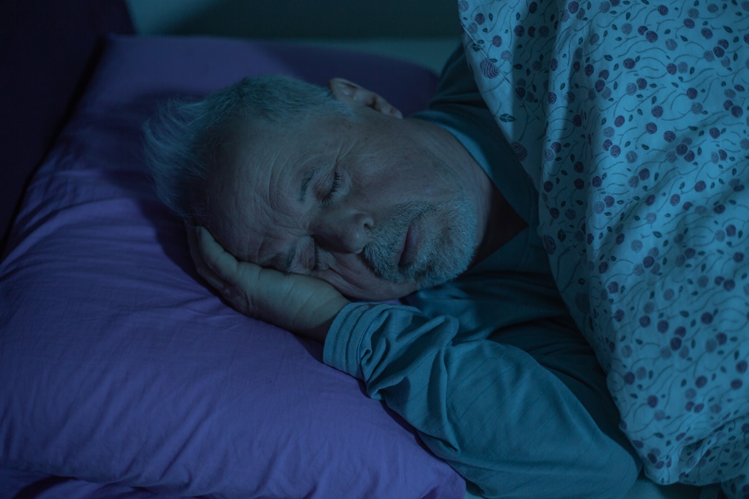 Senior man sleeping in the middle of the night in a bed, deep sleep