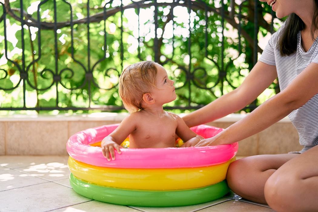 Little girl sits in an inflatable pool and looks at mom