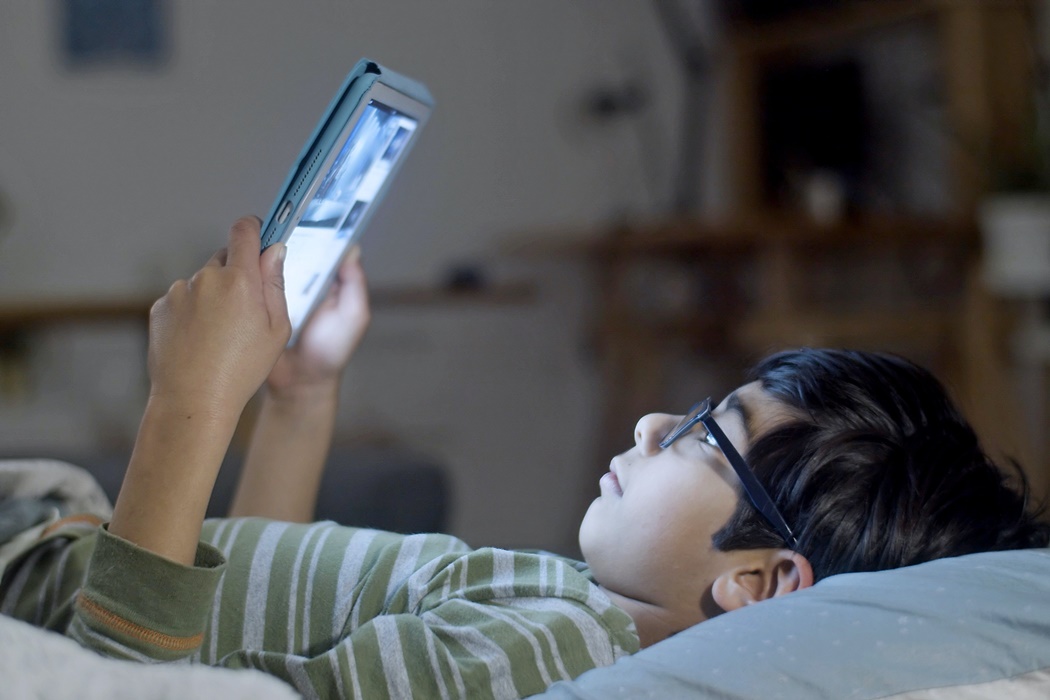 Boy playing tablet in bed