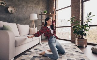 Full length body size view of attractive cool overjoyed cheerful girl dancing having fun alone at modern brick loft industrial home indoors.