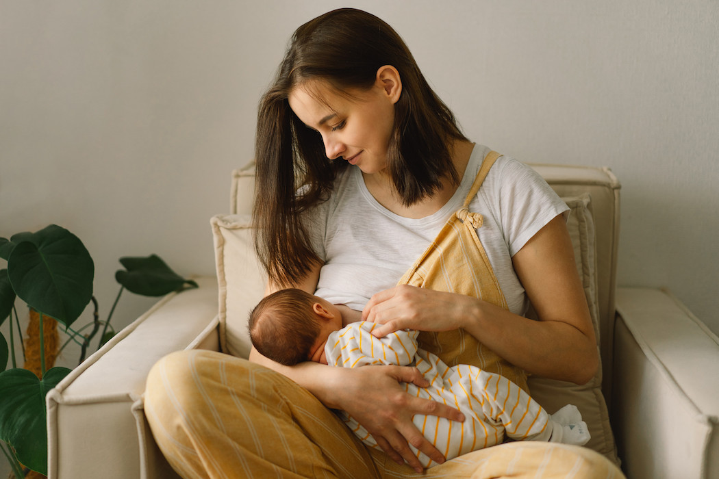 Newborn baby boy sucking milk from mothers breast. Portrait of mom and breastfeeding baby. Concept of healthy and natural baby breastfeeding nutrition.